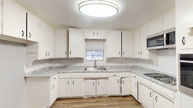 kitchen featuring sink, white cabinets, appliances with stainless steel finishes, and hardwood / wood-style floors