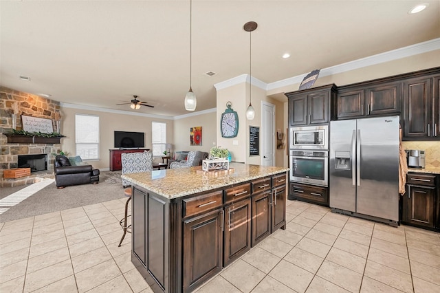 kitchen with hanging light fixtures, dark brown cabinets, stainless steel appliances, a kitchen island, and a kitchen bar