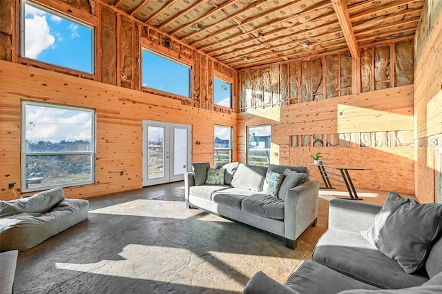 living room with a towering ceiling, wooden ceiling, wooden walls, and french doors