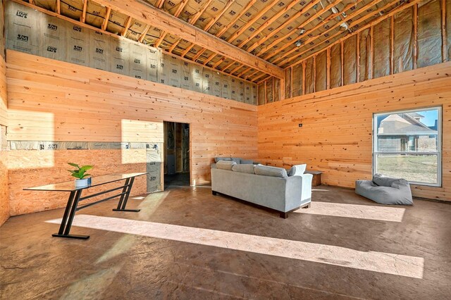 unfurnished living room with a towering ceiling and wood walls