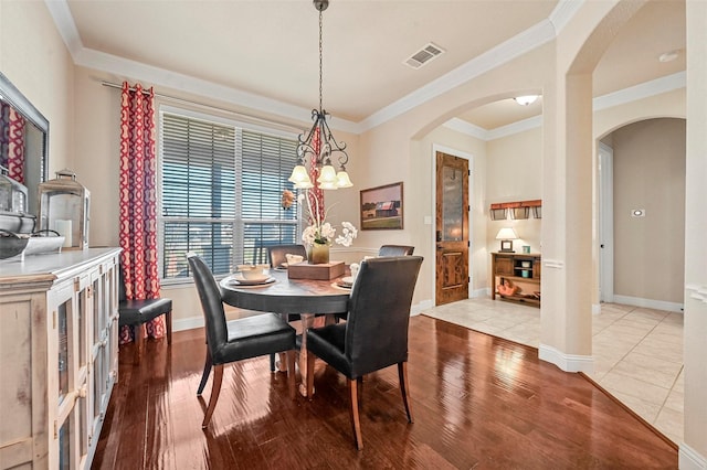 dining room with crown molding and light hardwood / wood-style flooring