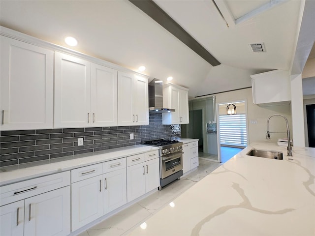 kitchen with high end stainless steel range oven, white cabinetry, wall chimney exhaust hood, and sink