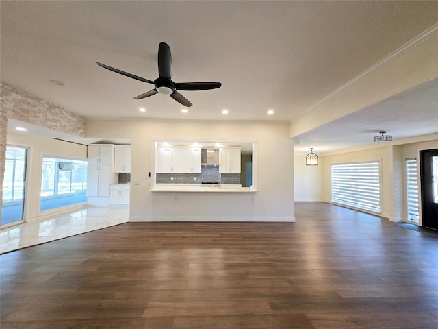 unfurnished living room featuring crown molding, dark wood-type flooring, and ceiling fan