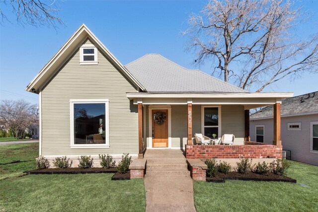 view of front facade with covered porch, central AC, and a front lawn