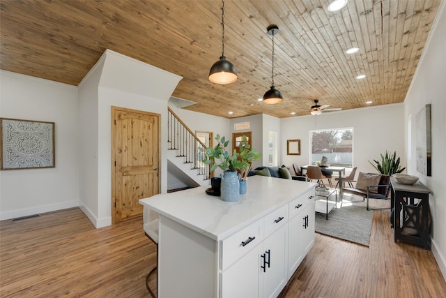 kitchen featuring decorative light fixtures, white cabinetry, a center island, light hardwood / wood-style floors, and wooden ceiling