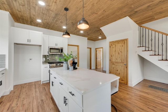 kitchen featuring decorative light fixtures, a center island, white cabinets, and appliances with stainless steel finishes