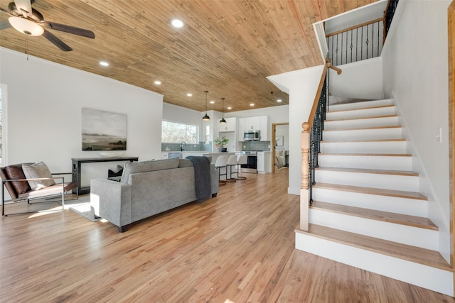 living room featuring ceiling fan, sink, light hardwood / wood-style flooring, and wooden ceiling