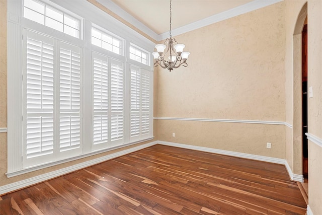 spare room with wood-type flooring, an inviting chandelier, and crown molding