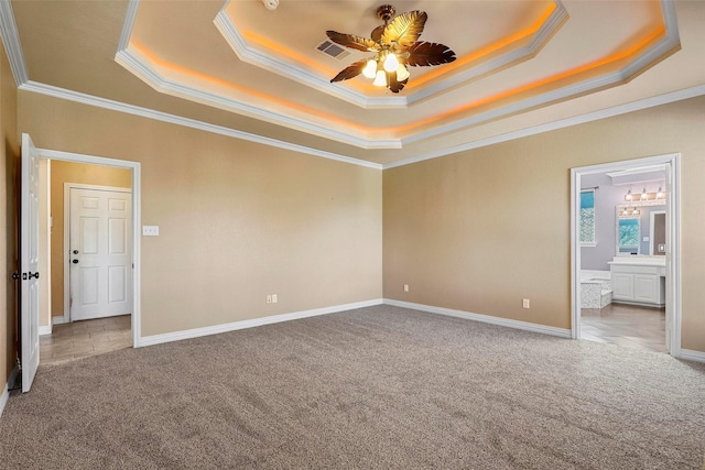 empty room with ceiling fan, carpet, a raised ceiling, and ornamental molding