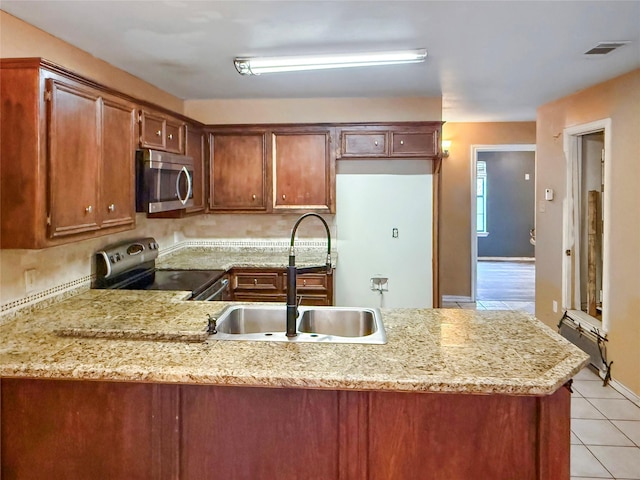 kitchen featuring sink, light tile patterned flooring, kitchen peninsula, and appliances with stainless steel finishes