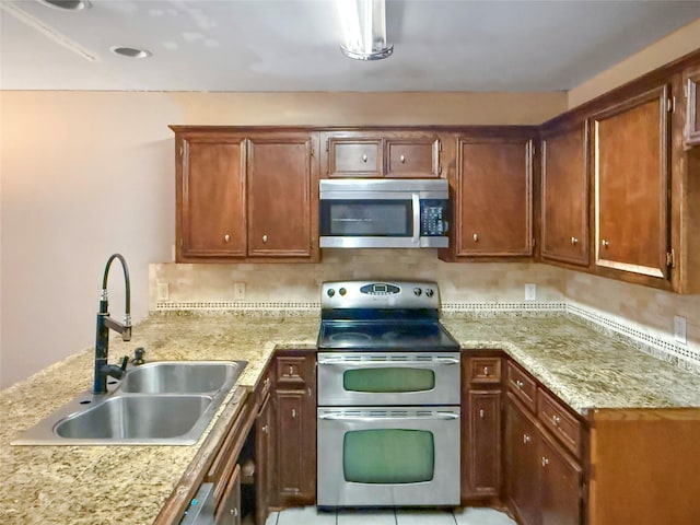 kitchen featuring light stone countertops, appliances with stainless steel finishes, sink, and kitchen peninsula