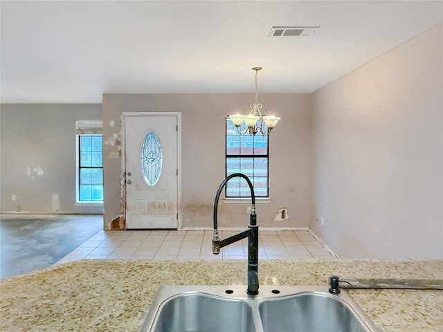 kitchen with an inviting chandelier, sink, light tile patterned floors, and hanging light fixtures