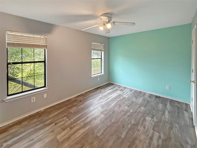 empty room with plenty of natural light, hardwood / wood-style floors, and ceiling fan