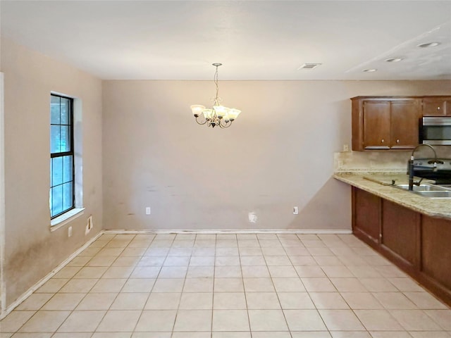 kitchen featuring light tile patterned flooring, a chandelier, hanging light fixtures, stainless steel appliances, and light stone countertops