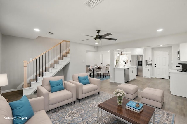 living room featuring sink, light hardwood / wood-style flooring, and ceiling fan