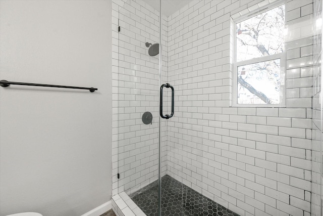 bathroom featuring a shower with shower door and toilet