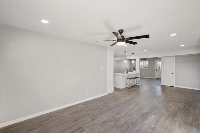 unfurnished living room with sink, dark hardwood / wood-style floors, and ceiling fan