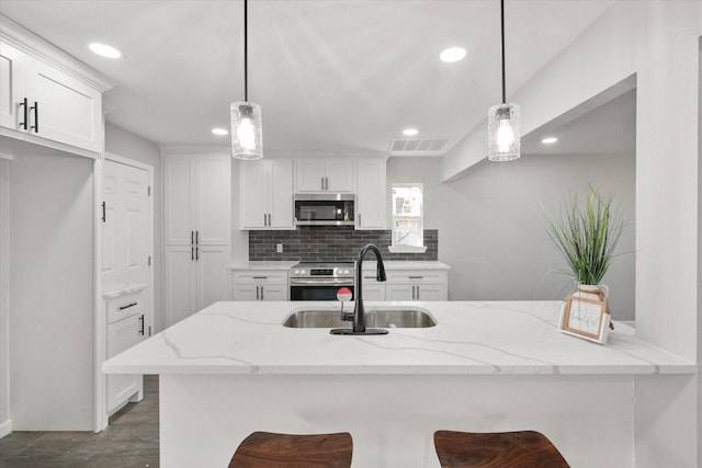 kitchen with white cabinets, pendant lighting, appliances with stainless steel finishes, and a breakfast bar area