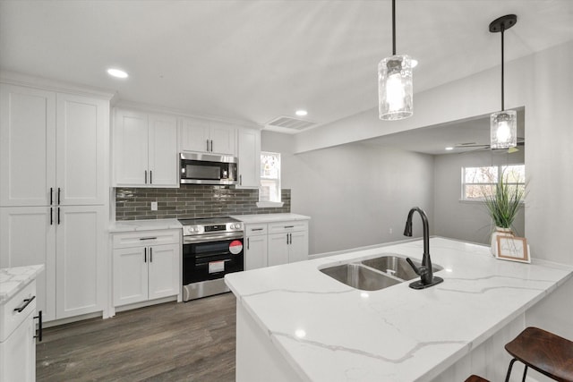 kitchen with pendant lighting, sink, white cabinetry, light stone countertops, and stainless steel appliances