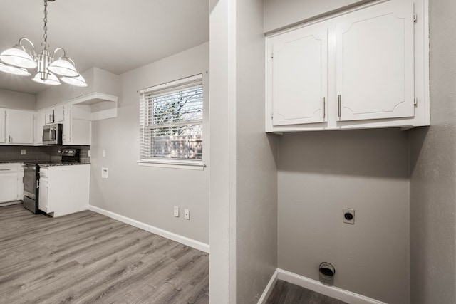 laundry room featuring light hardwood / wood-style floors, cabinets, a notable chandelier, and hookup for an electric dryer