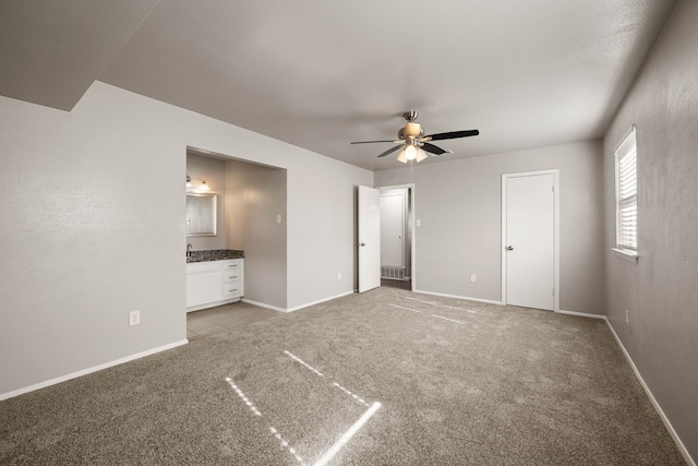 unfurnished bedroom featuring light carpet, ensuite bath, and ceiling fan