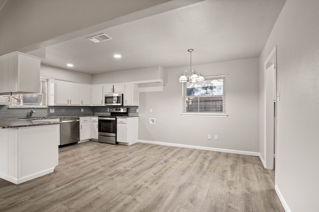 kitchen with decorative light fixtures, white cabinets, light wood-type flooring, a chandelier, and stainless steel appliances