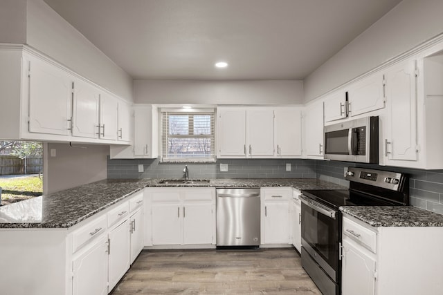 kitchen with sink, white cabinetry, appliances with stainless steel finishes, and dark stone counters