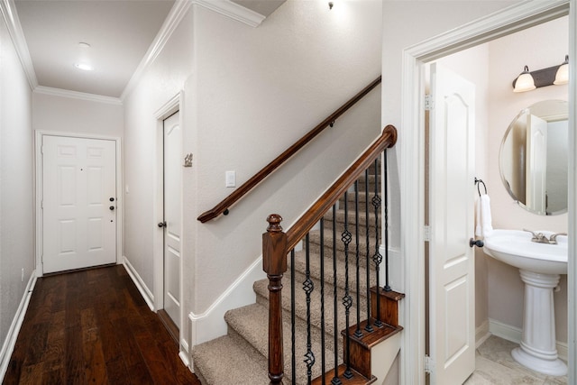 stairway with sink, crown molding, and wood-type flooring