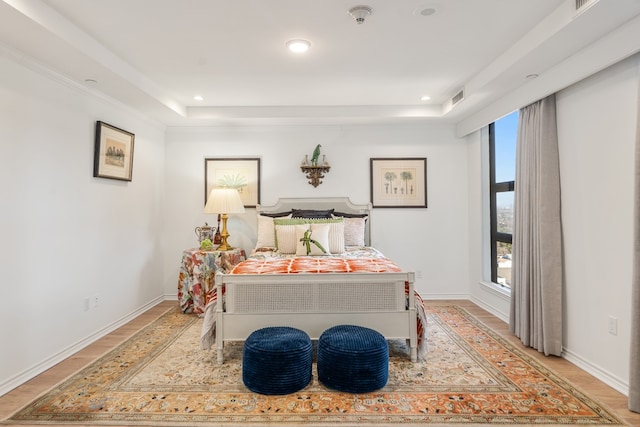 bedroom featuring a raised ceiling and light wood-type flooring