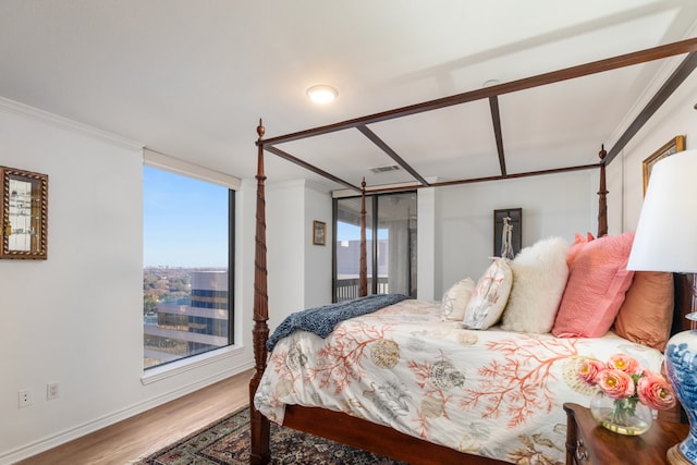 bedroom with a wall of windows, ornamental molding, and hardwood / wood-style floors