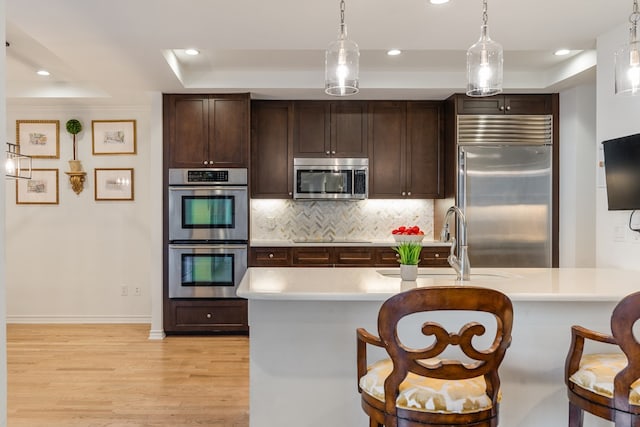 5909 Luther Ln Unit 2000, Dallas, TX 75225 - kitchen with baseboards, a raised ceiling, light wood finished floors, and stainless steel appliances