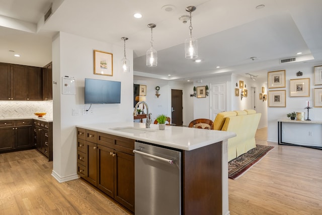 kitchen with light hardwood / wood-style floors, dishwasher, sink, and kitchen peninsula