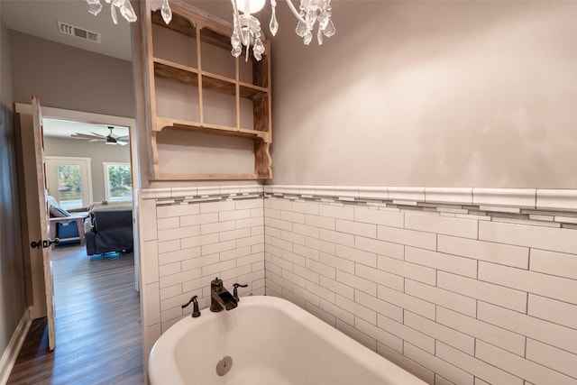 bathroom featuring hardwood / wood-style flooring, ceiling fan, tile walls, and a bathing tub