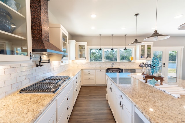 kitchen featuring white cabinetry, stainless steel appliances, sink, wall chimney exhaust hood, and pendant lighting