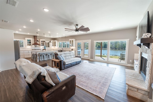 living room with sink, ceiling fan, dark wood-type flooring, a fireplace, and french doors