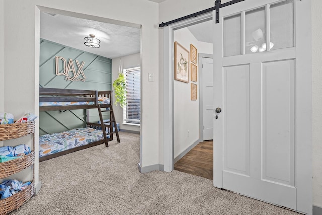 bedroom with a barn door, a textured ceiling, and carpet