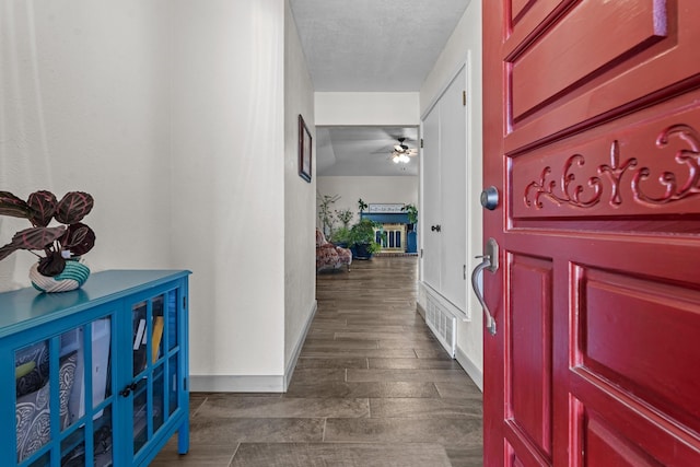 foyer featuring ceiling fan, dark wood-type flooring, and a textured ceiling