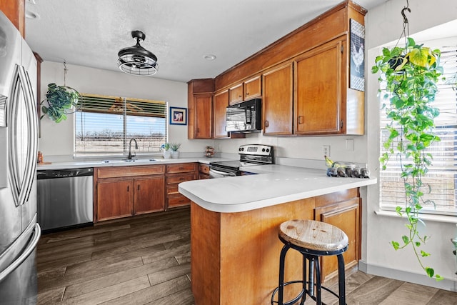 kitchen featuring dark hardwood / wood-style floors, a breakfast bar, sink, kitchen peninsula, and stainless steel appliances