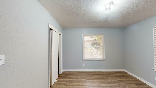 unfurnished bedroom with dark wood-type flooring, a textured ceiling, and a closet