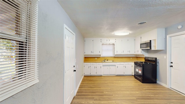 kitchen with light hardwood / wood-style flooring, sink, white cabinetry, a textured ceiling, and black gas range oven