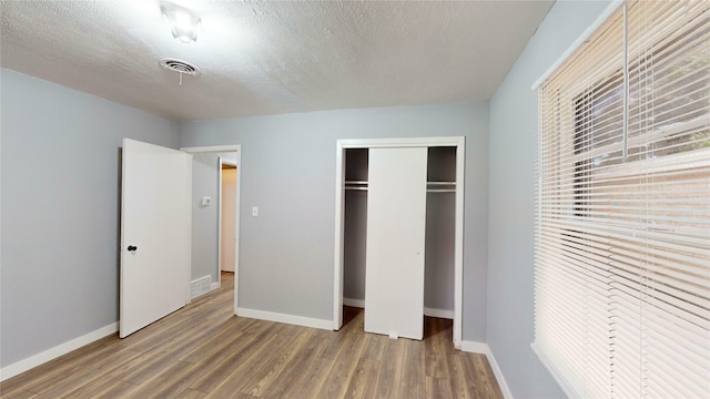 unfurnished bedroom featuring hardwood / wood-style floors, a textured ceiling, and a closet