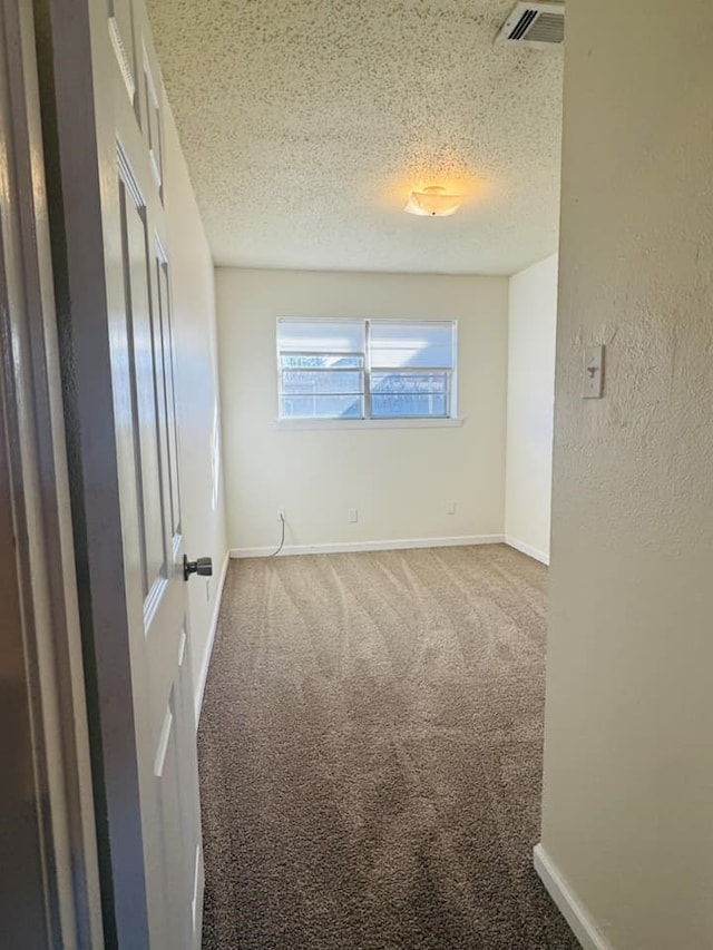 carpeted empty room with a textured ceiling