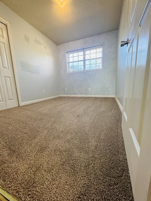 unfurnished room featuring a textured ceiling and carpet