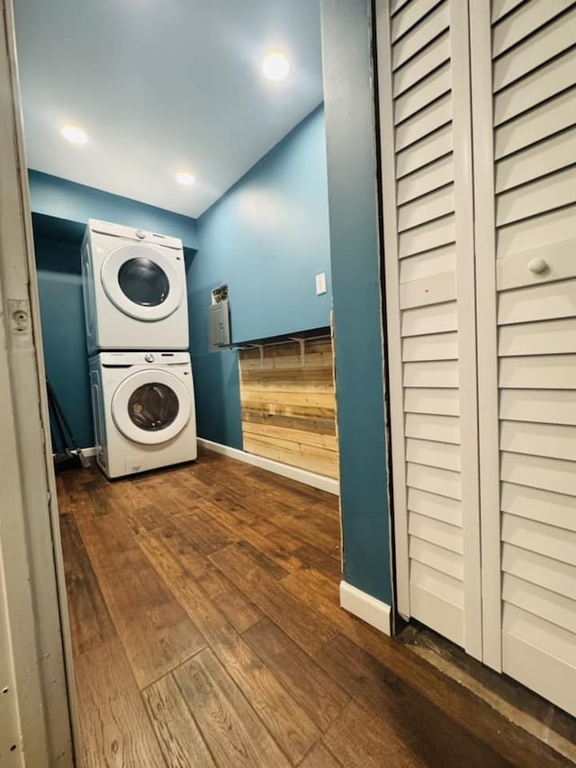 laundry room featuring dark hardwood / wood-style floors, wooden walls, and stacked washer and clothes dryer