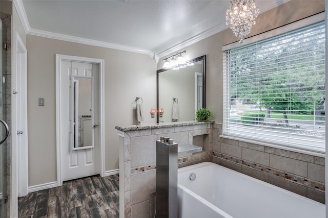 bathroom featuring ornamental molding, a bathing tub, hardwood / wood-style floors, and a notable chandelier