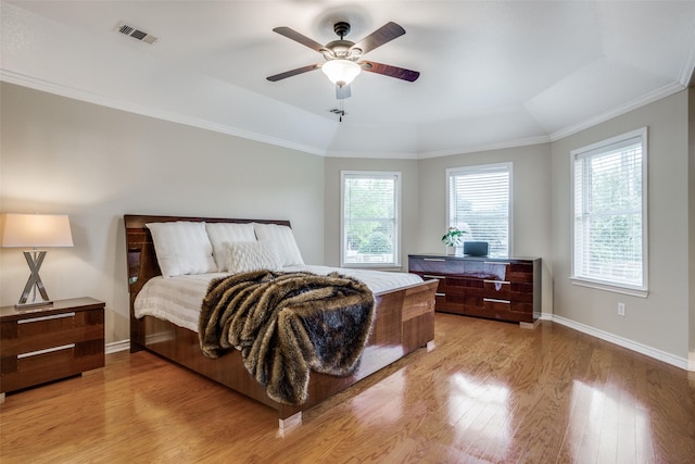 bedroom featuring a tray ceiling, ornamental molding, ceiling fan, and light wood-type flooring