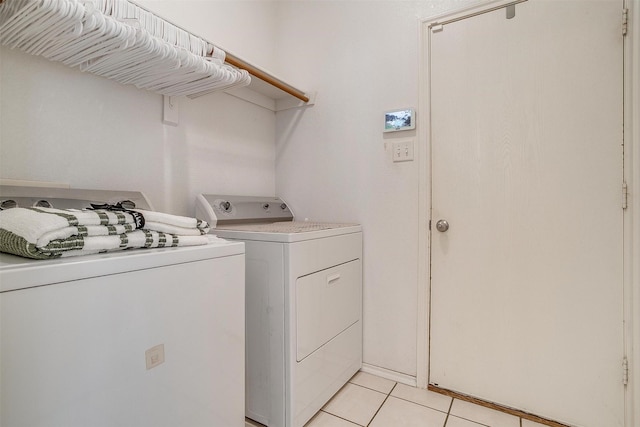 clothes washing area with washing machine and clothes dryer and light tile patterned floors