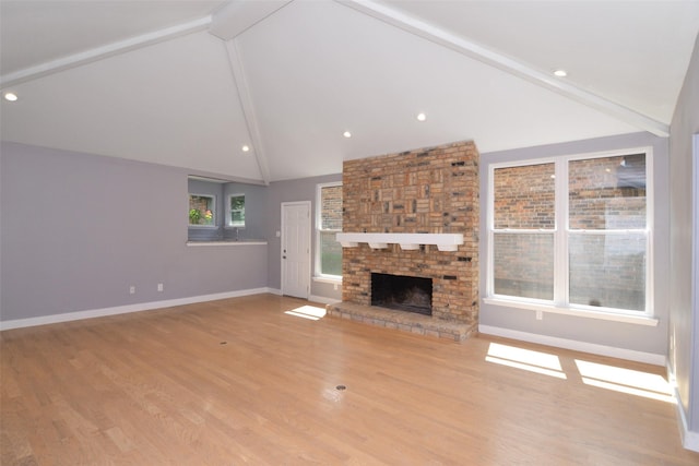 unfurnished living room with light hardwood / wood-style floors, high vaulted ceiling, beamed ceiling, and a fireplace