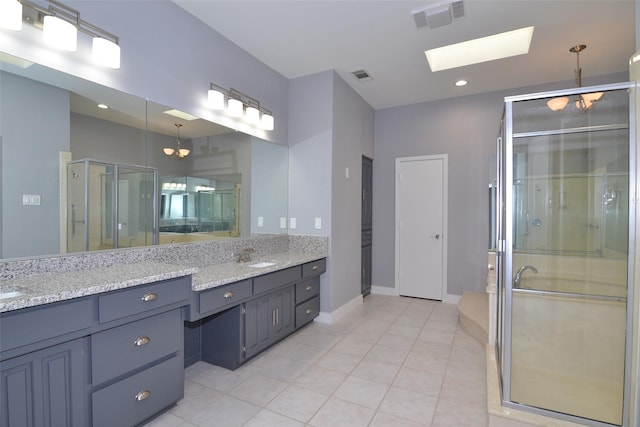 bathroom featuring tile patterned floors, a shower with door, a skylight, and vanity