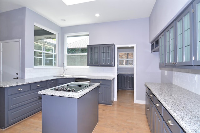 kitchen featuring black electric cooktop, light hardwood / wood-style floors, a center island, and tasteful backsplash